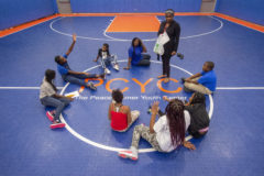 Peace Corner Youth Center kids sitting in a circle on the basketball court